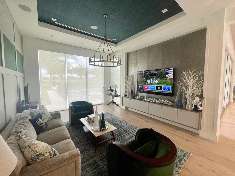 Contemporary living room with large windows, motorized shades, and a wall-mounted TV in a stylish, open space.