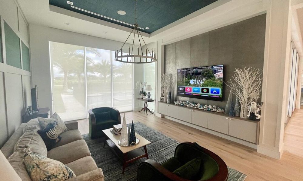 Contemporary living room with large windows, motorized shades, and a wall-mounted TV in a stylish, open space.