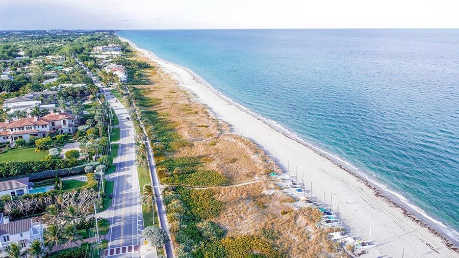 Aerial view of a long coastline next to homes and a quiet road